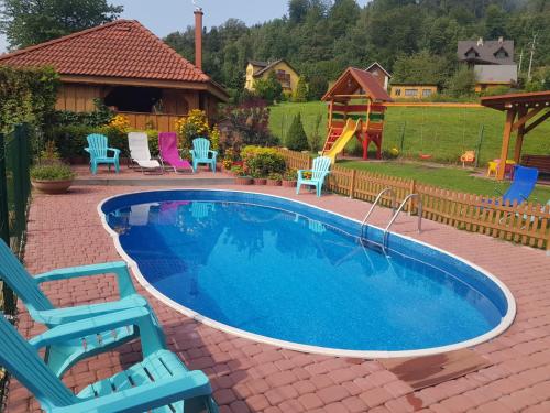 a swimming pool with chairs and a slide at Willa i domki Victoria in Wisła