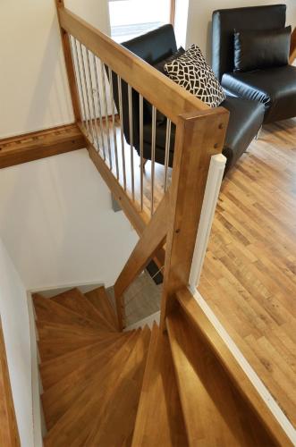 a wooden stairway with a chair and a couch at FeWo Jung in Falkensee
