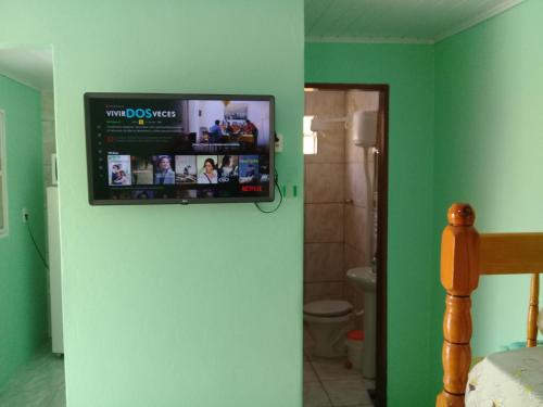 una televisione appesa a un muro in bagno di Pousada Cabral a São Gabriel