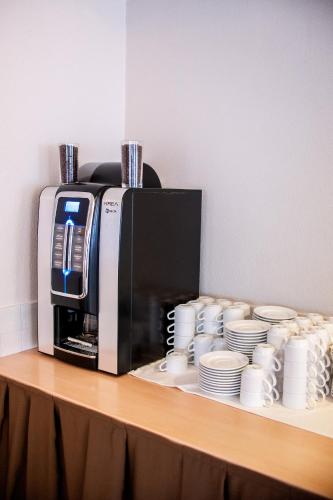 a counter with a coffee maker and cups and plates at Hotel Bacco Rooms and Breakfast in Pietra Ligure