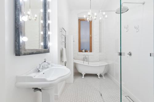 Dream Apartment by LoftAffair في كراكوف: حمام أبيض مع حوض ومغسلة