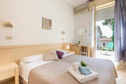 a bedroom with a bed and a window and a table at Hotel Verde Luna in Cervia