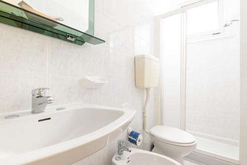 a white bathroom with a sink and a toilet at Hotel Verde Luna in Cervia