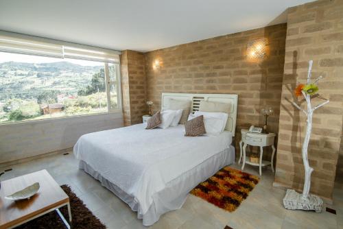 a bedroom with a large bed and a large window at Bella Tierra Hotel Boutique in Tibasosa