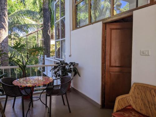 a balcony with a table and chairs and a door at Michèle's Garden in Anjuna