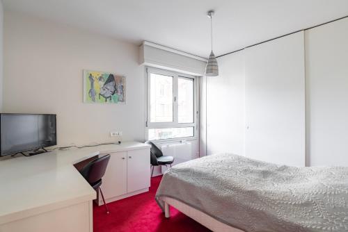 a bedroom with a bed and a desk and a tv at Strasbourg - Cosy Contades in Strasbourg