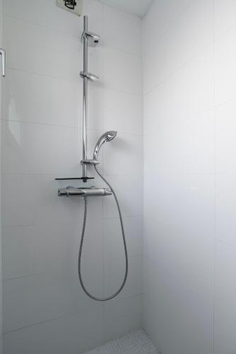 La salle de bains est pourvue d'un pommeau de douche et d'un mur blanc. dans l'établissement CityCosy-Strasbourg - Chic Oberlin Contades, à Strasbourg