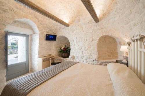 Un dormitorio con una cama en una pared de piedra. en Trulli Resort Aia Piccola, en Alberobello
