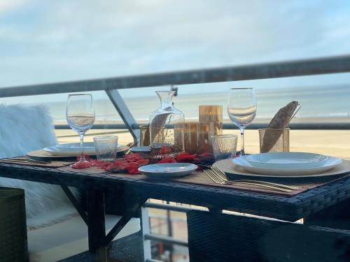 a table with plates and wine glasses on a balcony at Superbe Appart vue mer avec balcon in Blankenberge