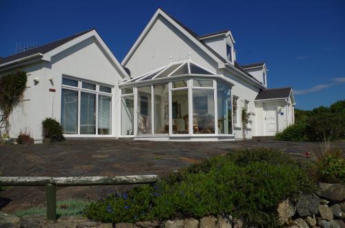 ein weißes Haus mit großen Fenstern in der Unterkunft Anam Sona SeaView B&B in Caherkeen