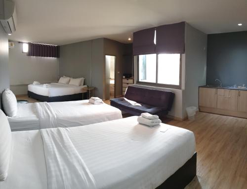 a hotel room with two beds and a couch at Wara Boutique Hotel in Udon Thani