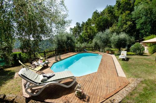 a swimming pool on a wooden deck with two lounge chairs around it at Podere L'Istrice in Massa e Cozzile