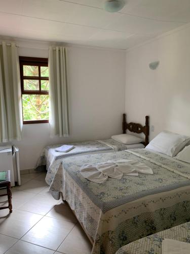 a bedroom with two beds and a window at Pousada Recanto da Mata in Marechal Floriano