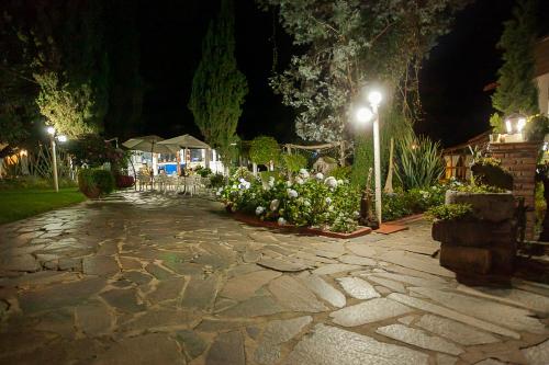 a stone walkway at night with lights and flowers at Htl & Villas Las Glorias Mazamitla, céntricas, parking, jardín in Mazamitla