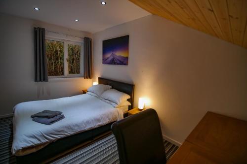 a bedroom with a bed and a chair and a window at Waterfall Lodge in Pont-Nedd-Fechan