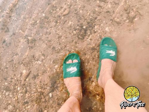 a person in green shoes standing in the water at RiverTree House in Nong Khai