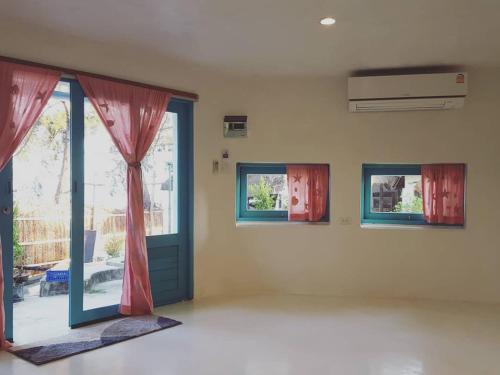 a room with a door and two windows and a balcony at Maliblues Bed & Art Gallery in Chumphon
