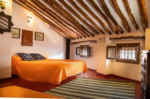 CarcabueyにあるCasilla Dalea en Carcabuey, descubre el interior de Andaluciaのベッドルーム1室(オレンジ色の毛布付きのベッド1台付)