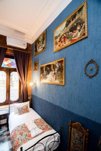a bedroom with a blue wall with a bed and paintings at Tiflis Inn Boutique Hotel in Tbilisi City
