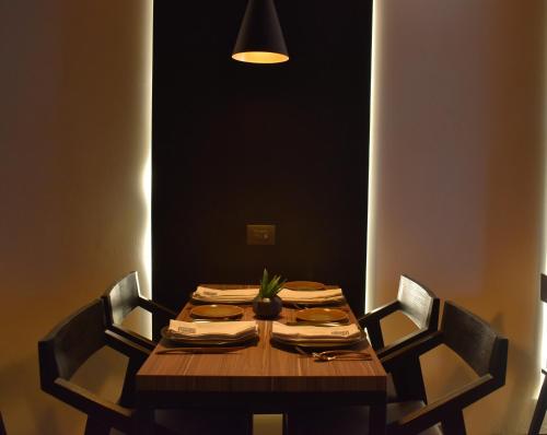 a wooden table with two chairs and a light fixture at Casa de la Luz Hotel Boutique in Mexico City