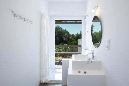 a white bathroom with a sink and a mirror at Villa Mavrades in Sivota