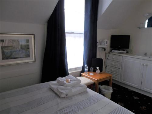 a bedroom with a bed and a tv and a window at The Beaumont in Sittingbourne