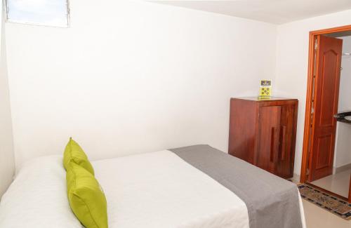 a bedroom with a white bed and a wooden cabinet at Ayenda 1131 Casa Valencia in Manizales