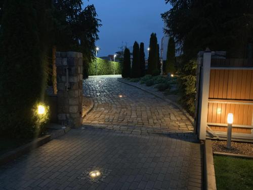 a cobblestone driveway at night with a gate at Domki Wczasowe Papaya in Kołobrzeg