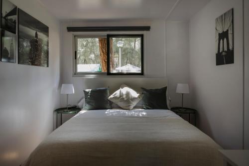 Un dormitorio con una cama con dos lámparas y una ventana. en Camping Giralda, en Huelva