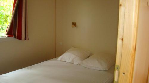 1 cama con 2 almohadas en una habitación en CAMPING LES GRAVES, en Saint-Pierre-Lafeuille