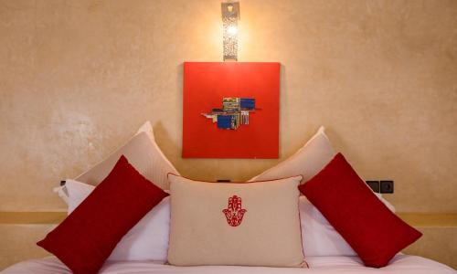 a bedroom with a bed with red and white pillows at Riad Azawad in Merzouga