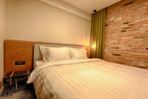 a bedroom with a bed and a brick wall at Nani Nani Boutique in Braşov