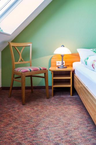 a bedroom with a bed and a chair and a table at Hotel Hus Achtern Diek in Insel Neuwerk
