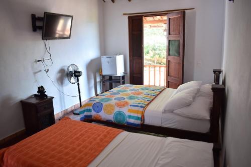 a bedroom with two beds and a television and a window at El Zaguan in Barichara