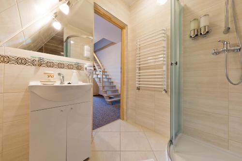 a bathroom with a sink and a shower and a staircase at Pokoje "u Kuruców" in Bukowina Tatrzańska