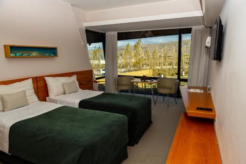 a hotel room with two beds and a table and a window at Design Suites Calafate in El Calafate