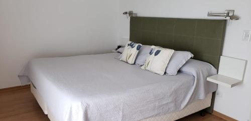1 dormitorio con cama blanca y cabecero verde en Torre Alberti Apartments en Mar del Plata