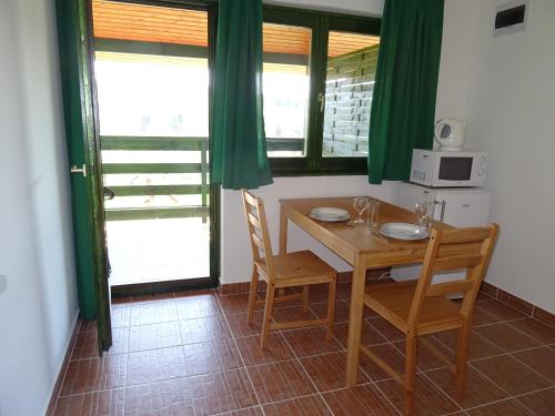 a kitchen with a table and chairs and a microwave at Kisrejtek Apartmanház in Lispeszentadorján