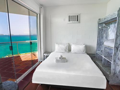 1 dormitorio con cama blanca y vistas al océano en Apa Pau Brasil, en Búzios