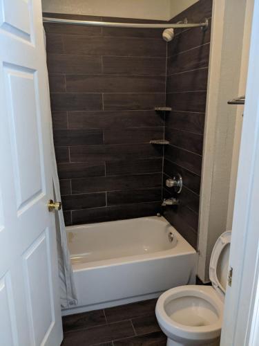 a bathroom with a white tub and a toilet at Key West Inn - Roanoke in Roanoke