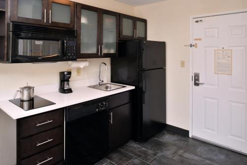 a kitchen with a sink and a black refrigerator at Candlewood Suites Winchester by IHG in Winchester