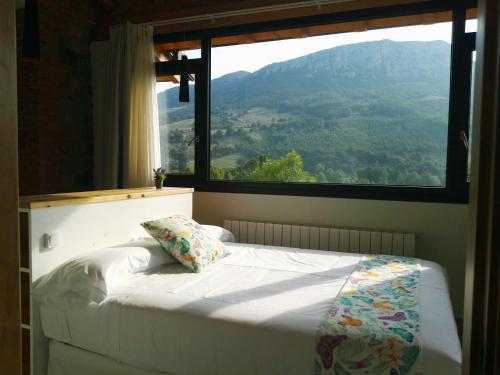 Bett in einem Zimmer mit einem großen Fenster in der Unterkunft La Onda in Ramales de la Victoria