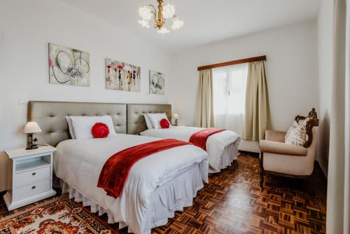 a bedroom with two beds with red pillows and a chair at City View Gardens I in Funchal