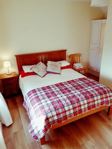 a bedroom with a bed with a plaid blanket at Granny Dens in Donegal