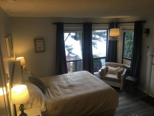 a bedroom with a bed and a chair and windows at Long Lake Waterfront Bed and Breakfast in Nanaimo