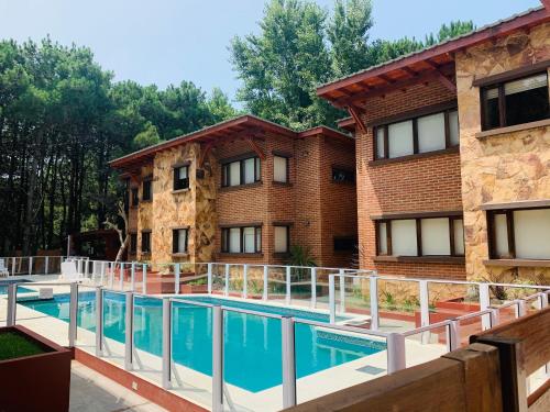 a building with a swimming pool in front of a building at Departamentos Le Forêt in Mar de Ajó