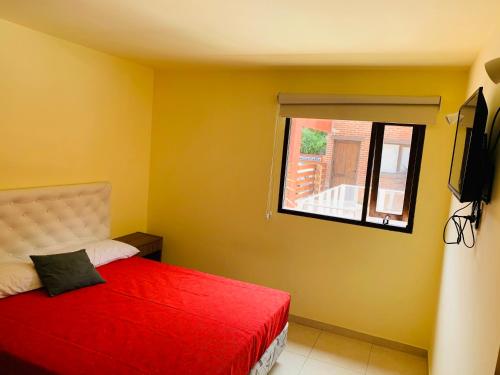 a bedroom with a red bed and a window at Departamentos Le Forêt in Mar de Ajó