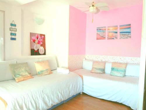 two beds in a room with pink and purple walls at LOFT DOS MARES- Parking Gratis - 1 Línea de Mediterráneo - Terraza - WIFI in La Manga del Mar Menor