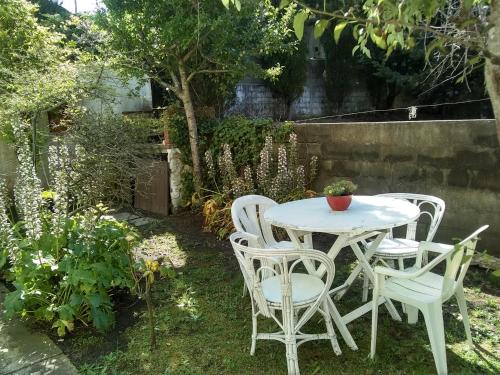 una mesa y sillas blancas en un jardín del Hotel La Terraza de Villa Gesell