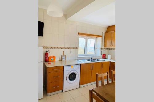 a kitchen with a washing machine and a sink at Beach House (Leirosa) in Figueira da Foz